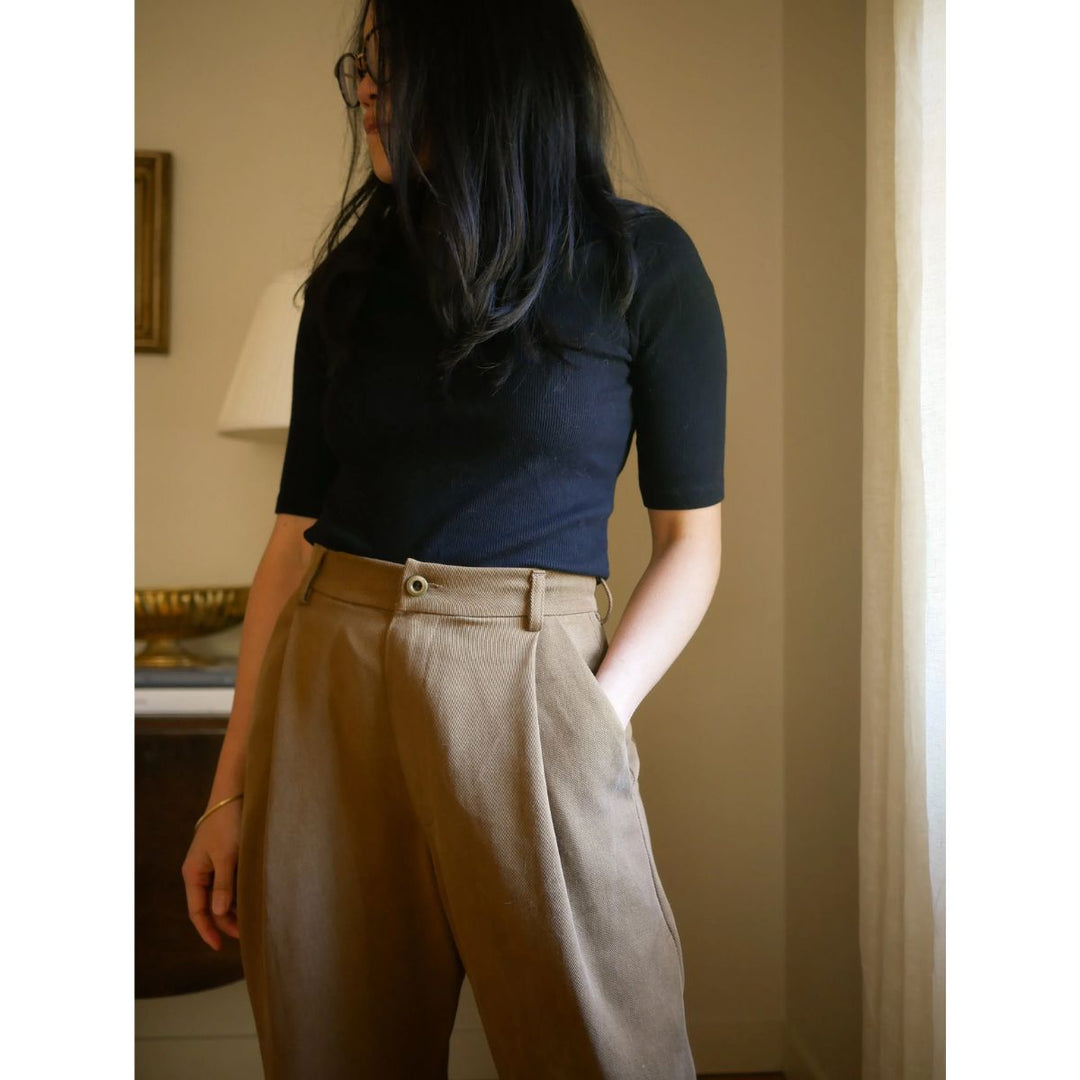 Person wearing a navy top and beige pants in an indoor setting