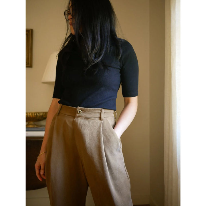 Person wearing a navy top and beige pants in an indoor setting