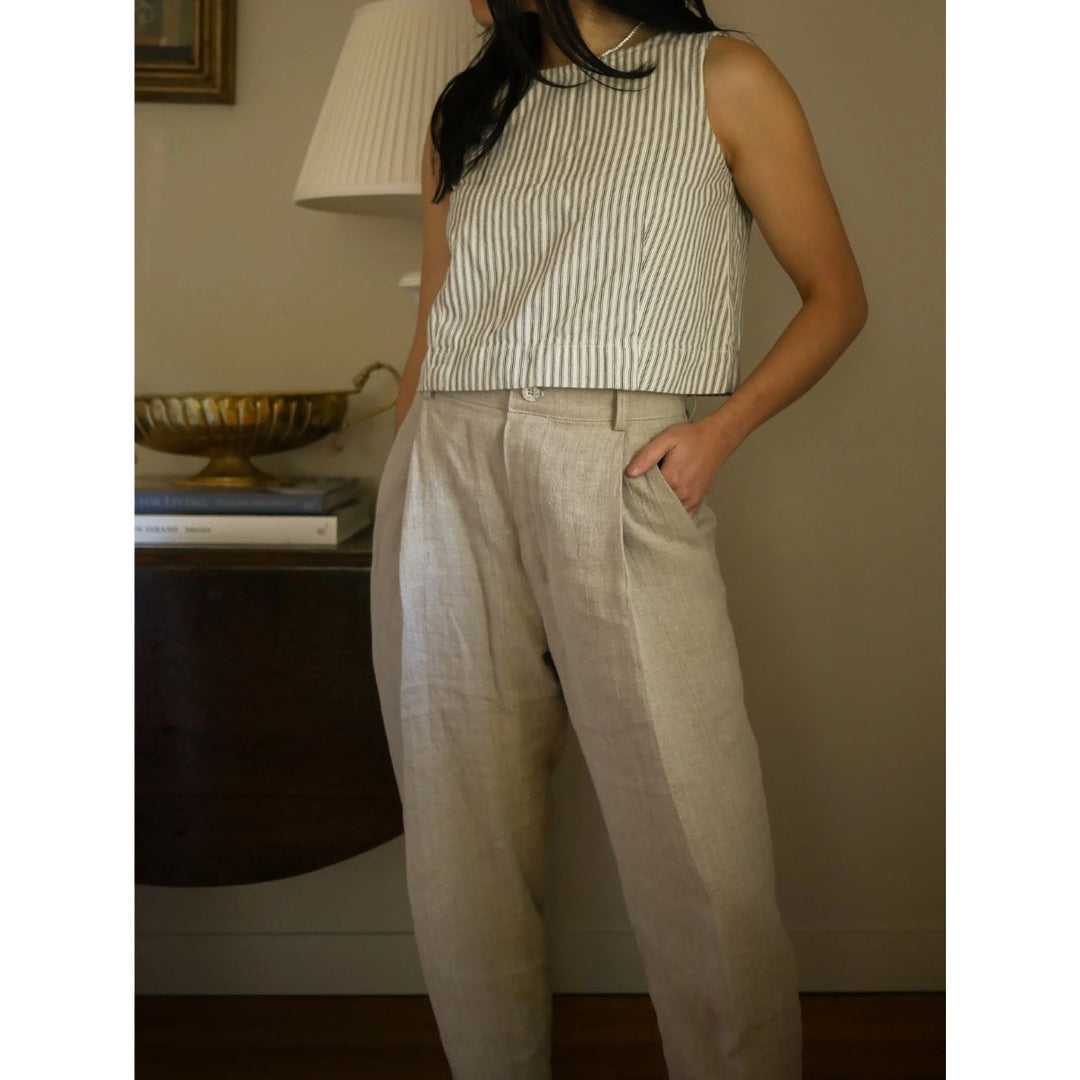 Person wearing a striped sleeveless top and beige pants in an indoor setting.