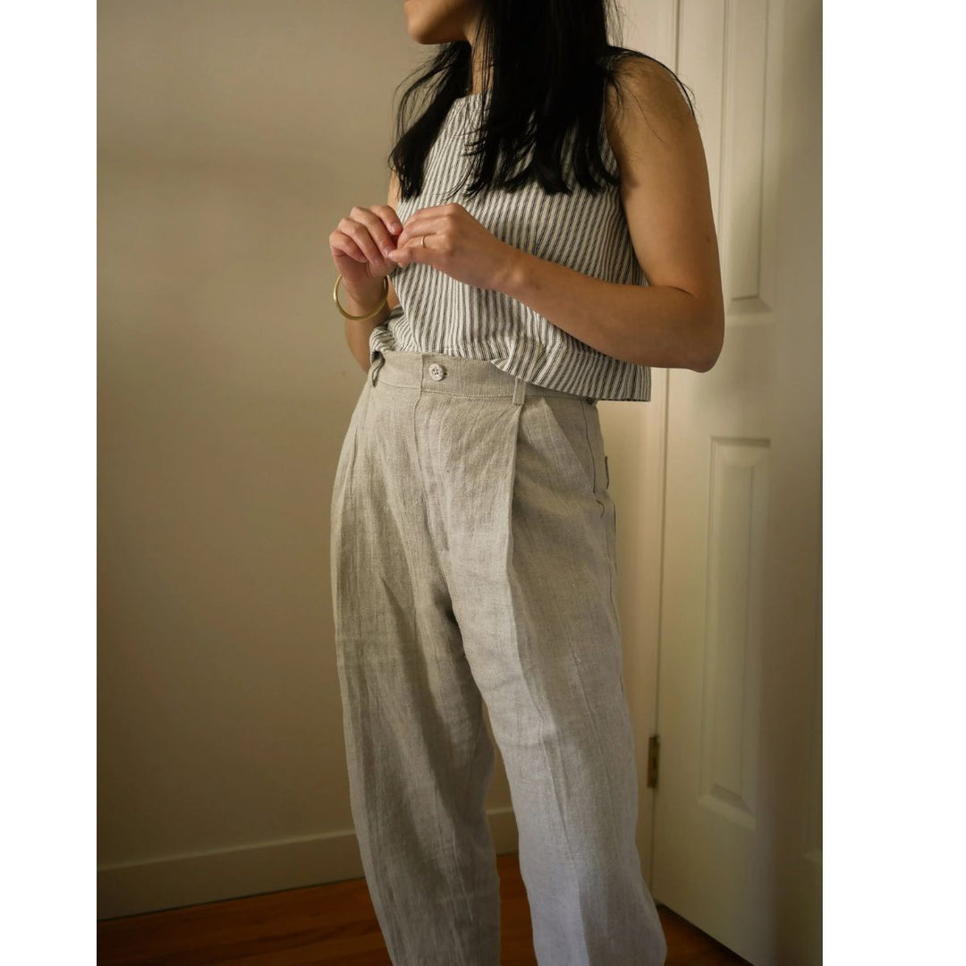 Person wearing a striped sleeveless top and light-colored pants indoors.