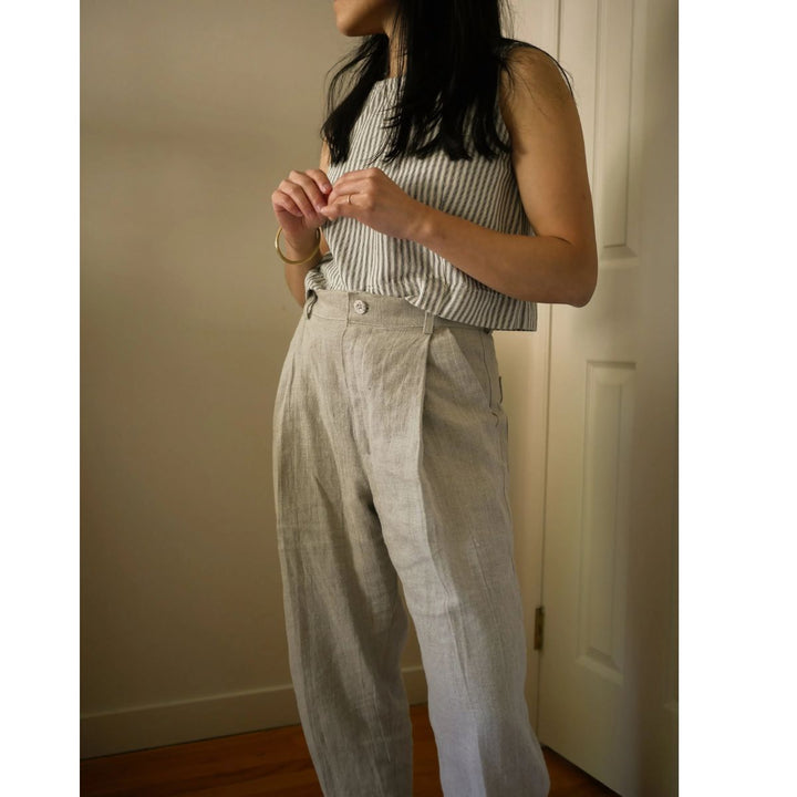 Person wearing a striped sleeveless top and light-colored pants indoors.