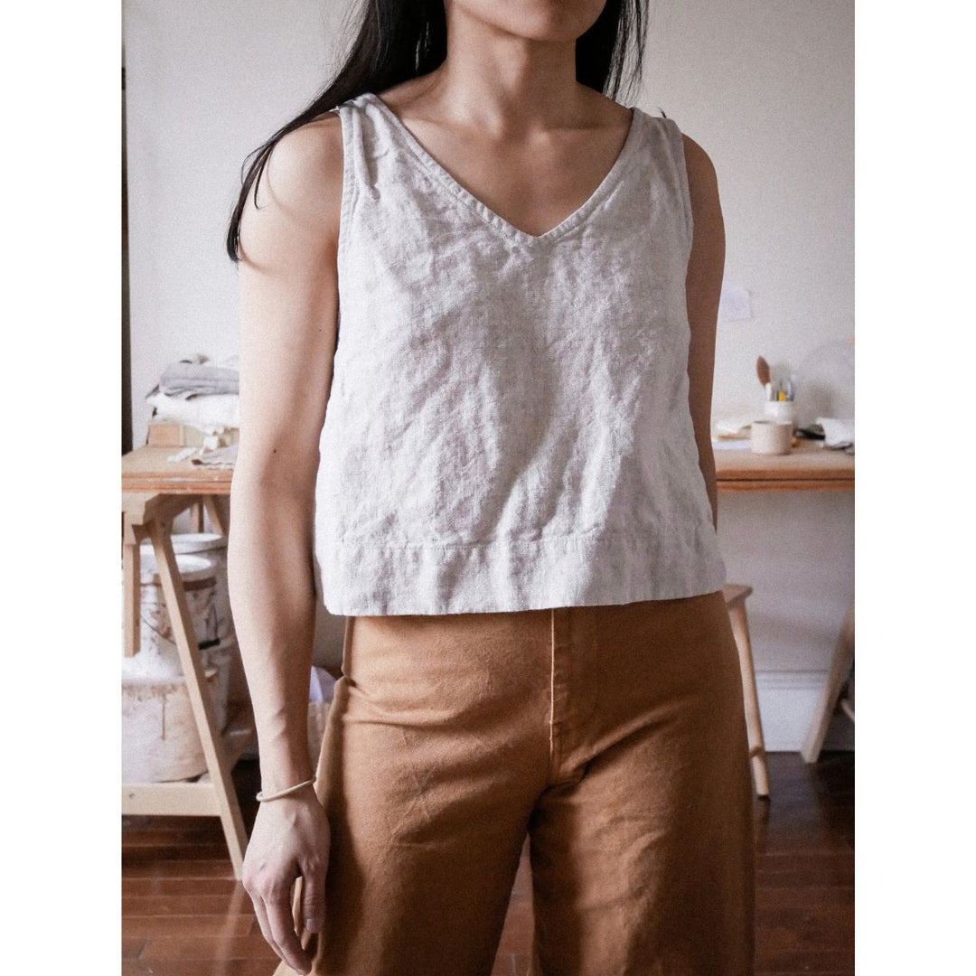 Person wearing a light-colored tank top and brown pants in a casual setting.