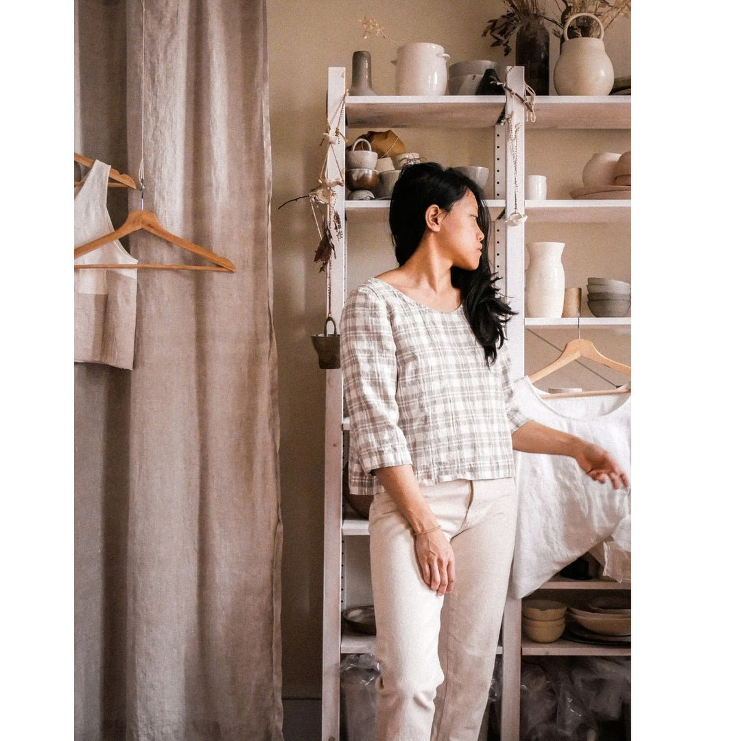 Woman standing in a room with shelves and a curtain