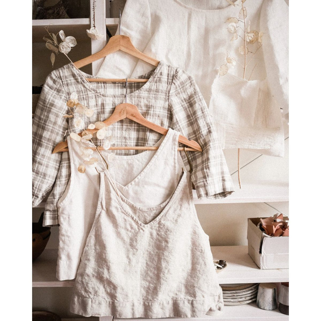 Two dresses hanging on wooden hangers with a white background