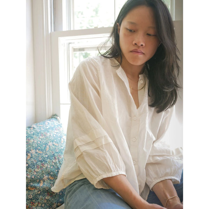 Person wearing a white shirt sitting in a softly lit room.