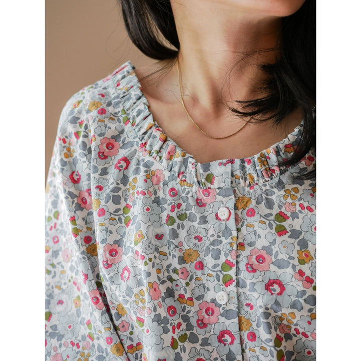 Close-up of a person wearing a floral blouse with a neutral background